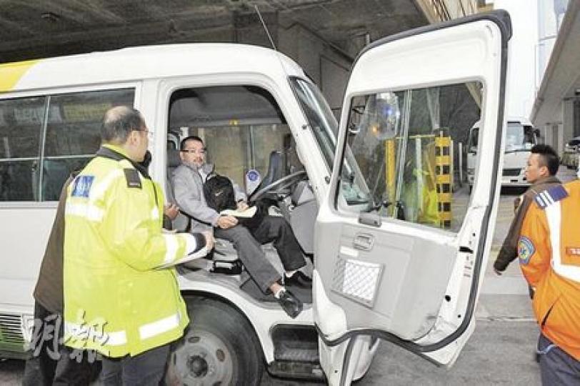 下車險被撞的復康巴士司機驚魂甫定後，坐在車上向警員講述經過。復康巴士車門則整扇被貨車撞歪。（蔡方山攝）