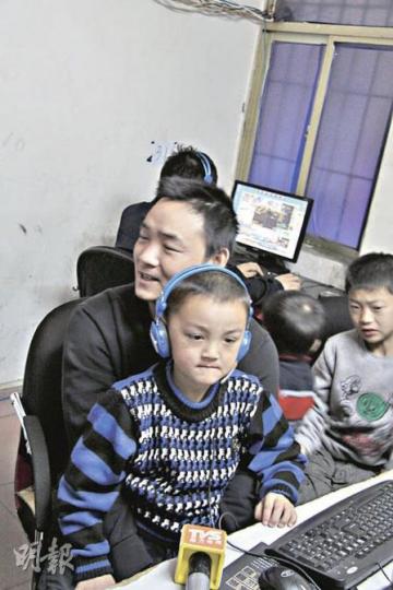 彭高峰一家四口就住在網吧內的閣樓上。圖為彭高峰上周四在深圳抱着兒子接受媒體採訪。（麥俊攝）