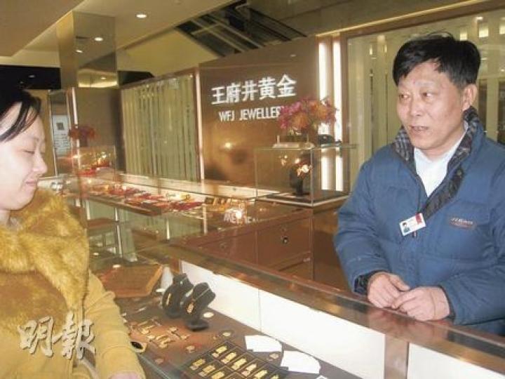「王府井黃金」店員正向客人推介金飾,他指早前銷情非常好,但近期已逐漸降溫。(劉洪慶攝) 「王府井黃金」店員正向客人推介金飾,他指早前銷情非常好,但近期已逐漸降溫。(劉洪慶攝)