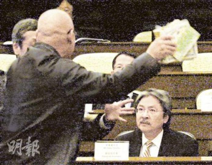 人民力量陳偉業(左圖背向鏡頭者)昨日手執2萬億元冥錢,灑向財政司長曾俊華(圖右),批評政府守着6000億元儲備不用。其間曾俊華一直表情木訥,如沒事發生般。立法會工作人員其後替他拿走冥錢(圖2)。陳最後被逐出議事廳。(李紹昌攝)(明報製圖) 人民力量陳偉業(左圖背向鏡頭者)昨日手執2萬億元冥錢,灑向財政司長曾俊華(圖右),批評政府守着6000億元儲備不用。其間曾俊華一直表情木訥,如沒事發生般。立法會工作人員其後替他拿走冥錢(圖2)。陳最後被逐出議事廳。(李紹昌攝)(明報製圖)