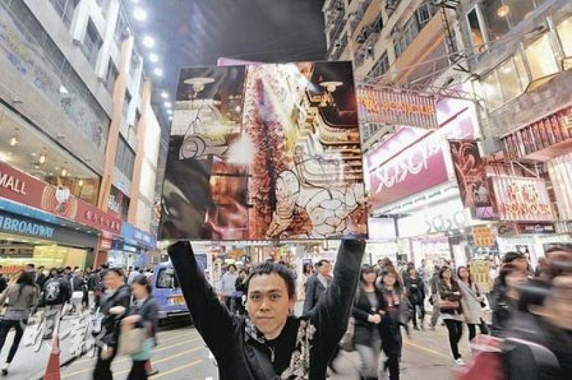 衛銘琛高舉經過加工的西洋菜街光污染相片,尤如外星人在大廈天台以死光掃射街上人群,以宣泄內心對光污染的不滿。(尹錦恩攝) 衛銘琛高舉經過加工的西洋菜街光污染相片,尤如外星人在大廈天台以死光掃射街上人群,以宣泄內心對光污染的不滿。(尹錦恩攝)