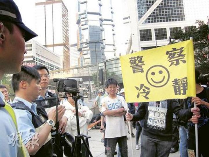 「爭取合理財富再分配聯席」僅數十人集會,警方卻派出多名警員拍攝現場情况。當警員以手提攝影機在人群中近距離拍攝時,有與會者舉起「警察冷靜」的橫額遮擋。(陳雪玲攝) 「爭取合理財富再分配聯席」僅數十人集會,警方卻派出多名警員拍攝現場情况。當警員以手提攝影機在人群中近距離拍攝時,有與會者舉起「警察冷靜」的橫額遮擋。(陳雪玲攝)