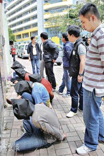 黑幫企圖壟斷秀茂坪區廢紙回收業,警方採取反黑行動打擊,涉案疑人黑布蒙頭面壁坐地等候帶署。(雲錦鋒攝) 黑幫企圖壟斷秀茂坪區廢紙回收業,警方採取反黑行動打擊,涉案疑人黑布蒙頭面壁坐地等候帶署。(雲錦鋒攝)