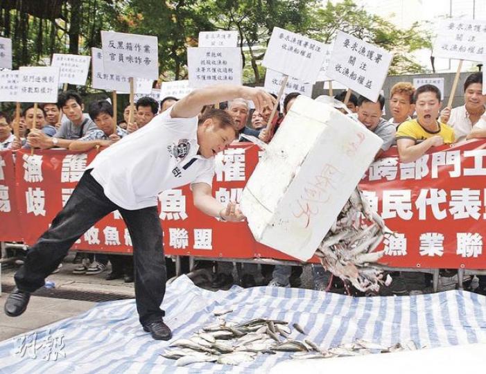 逾百名本港漁民不滿政府在本港海域禁拖網捕魚，趕絕他們生計，但賠償機制不公，昨在立法會門外怒拋倒魚抗議。（李紹昌攝）