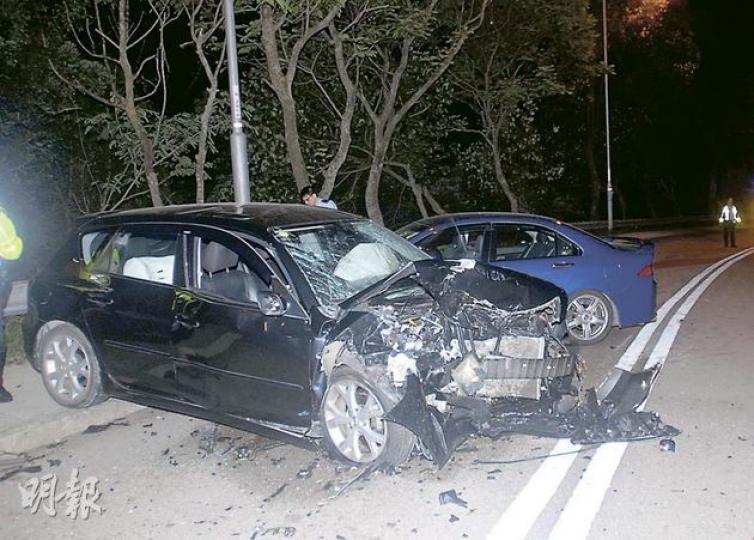車禍中，外籍男女駕乘的黑色私家車，被懷疑切線爬頭的藍色私家車迎頭猛撞，兩車均嚴重損毁。（蔡方山攝）