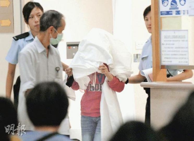 女傭（用布蒙頭者）事後自行往醫院求醫時遭揭發事件，被警方以「非法墮胎」罪名拘捕。（屈俊樂攝）