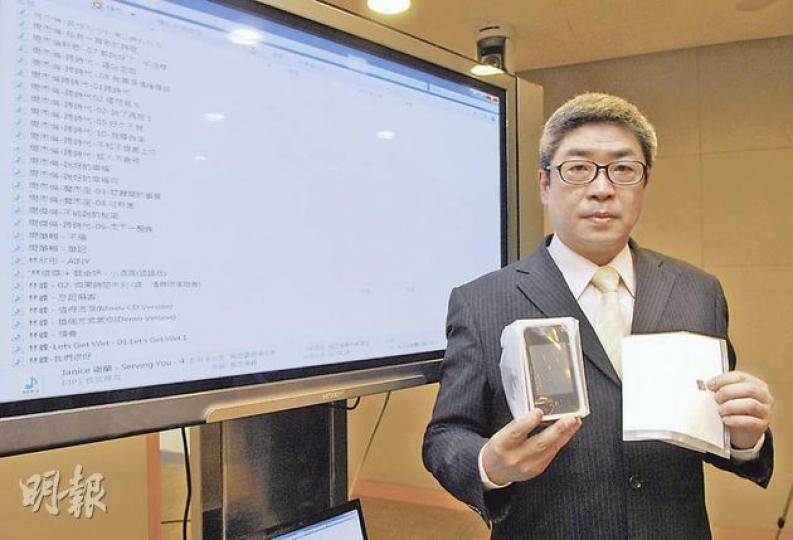 海關版權調查組指揮官關煜群博士,手持「山寨」手機及記憶卡,身後電腦顯示屏顯示卡內mp3歌曲名稱。(鍾炳然攝) 海關版權調查組指揮官關煜群博士,手持「山寨」手機及記憶卡,身後電腦顯示屏顯示卡內mp3歌曲名稱。(鍾炳然攝)