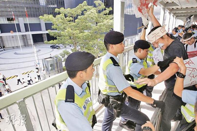 國務院副總理李克強昨午出席添馬艦新政府總部落成典禮,「女長毛」雷玉蓮(頭戴「平反六四」字句紙帽者)欲攀上鐵馬示威,大批機動部隊成員即抓緊鐵馬以防示威者倒下。圖左上方地面位置為新政府總部。(李紹昌攝) 國務院副總理李克強昨午出席添馬艦新政府總部落成典禮,「女長毛」雷玉蓮(頭戴「平反六四」字句紙帽者)欲攀上鐵馬示威,大批機動部隊成員即抓緊鐵馬以防示威者倒下。圖左上方地面位置為新政府總部。(李紹昌攝)