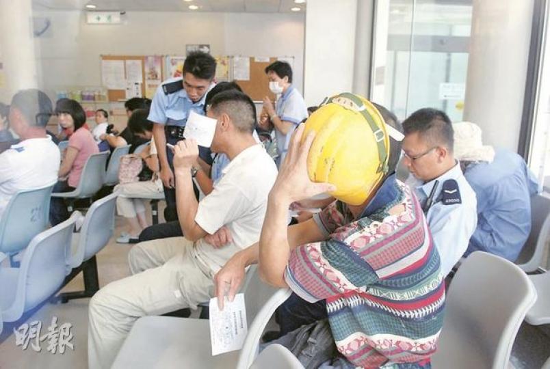 在新政府總部參與打鬥的工人，事後由警員押往醫院治理，看到記者拍照即掩面避開鏡頭。（雲錦鋒攝）