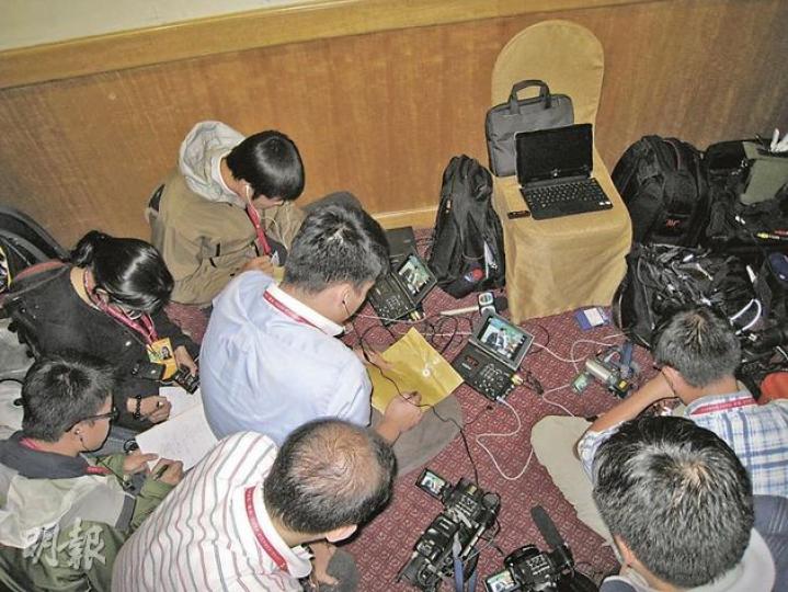 隨曾蔭權到新疆採訪的香港記者,由於不獲准進入場地內採訪,即使身處現場,亦只能圍在小播放機前觀看香港政府新聞處的錄影片段撰寫報道。圖為記者翻看及錄取片段的情况。(劉洪慶攝) 隨曾蔭權到新疆採訪的香港記者,由於不獲准進入場地內採訪,即使身處現場,亦只能圍在小播放機前觀看香港政府新聞處的錄影片段撰寫報道。圖為記者翻看及錄取片段的情况。(劉洪慶攝)