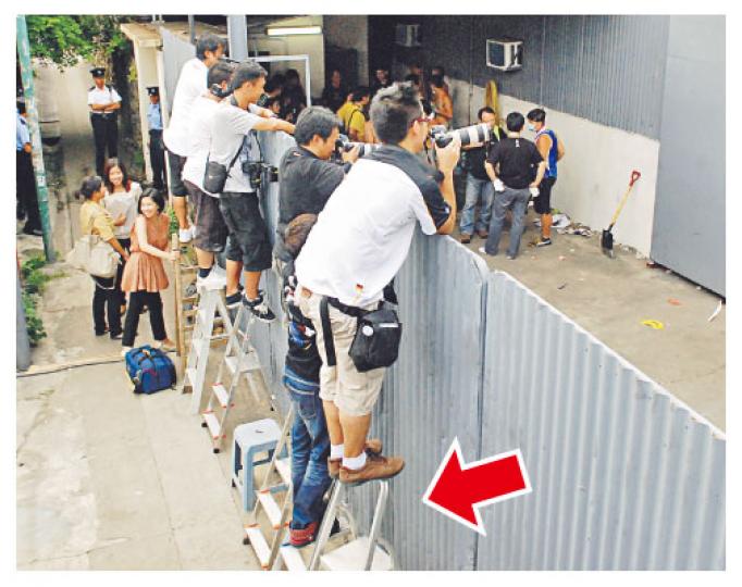屯門福亨村破獲本港歷來最大宗販運可卡因案,大批傳媒在場守候,為拍得有新聞價值場面,有人站到鐵梯頂部(箭嘴示)。(雲錦鋒攝) 屯門福亨村破獲本港歷來最大宗販運可卡因案,大批傳媒在場守候,為拍得有新聞價值場面,有人站到鐵梯頂部(箭嘴示)。(雲錦鋒攝)