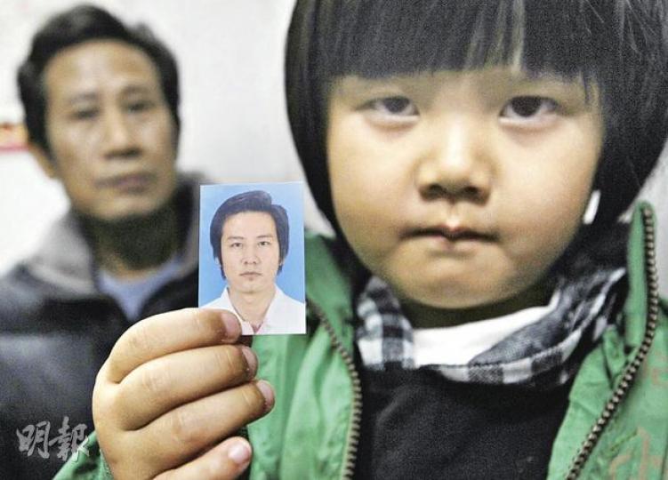 烏坎村維權領袖之一張建成被扣押,至今未獲釋,其女兒手持他的照片,默言無語,背後是建成的父親張水妹。(明報記者攝) 烏坎村維權領袖之一張建成被扣押,至今未獲釋,其女兒手持他的照片,默言無語,背後是建成的父親張水妹。(明報記者攝)