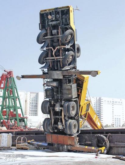 吊臂車與岸邊躉船呈「Ｔ」字形，長臂插入海中後，車身如同「站起來」。（楊嘉欣攝）吊臂車的長臂插落海中，幸有躉船擋着才不至全車「翻筋斗」跌下海。（郭慶輝攝）