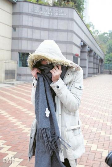 早年因癌症切除子宮的被告梁穎慧，疑因擔心癌病復發，連環在4間商店高買，昨被判感化 ，離開法院時以外套掩臉。（阮穎嘉攝）