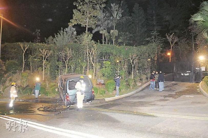 一輛客貨車泊在陳松青女兒家門外，被縱火焚毁，消防員到場開喉灌救。（蔡方山攝）