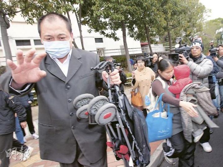 載着妻兒在路上與石油氣車追逐的七人車司機趙沛然，被判240小時社會服務令。他昨離庭後手持嬰兒車，同行女子則抱着一名幼童。（鄧宗弘攝）