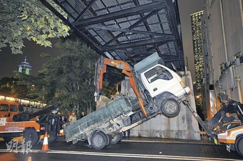 貨車尾斗的吊臂未收好，結果撞上山頂纜車架空天橋，車頭被扯起，司機被困在「半空」車廂內。（何家達攝） 吊臂撞上橋底的位置，剛巧是一個寫明限高4.1米的指示牌，顯示吊臂超出高度。（何家達攝）