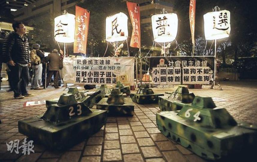 社民連昨晚在會展對出的中環廣場外集會,以孔明燈透射「全民普選」四個大字,表達對普選的渴求,又準備8架坦克車道具「恭迎」梁振英,批評梁在平反六四及《基本法》23條立法的議題上含糊其辭。(余俊亮攝) 社民連昨晚在會展對出的中環廣場外集會,以孔明燈透射「全民普選」四個大字,表達對普選的渴求,又準備8架坦克車道具「恭迎」梁振英,批評梁在平反六四及《基本法》23條立法的議題上含糊其辭。(余俊亮攝)