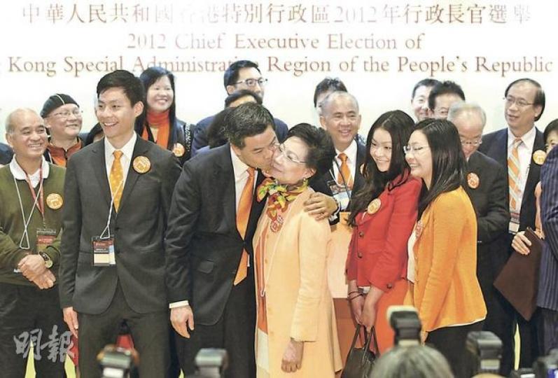 梁振英(左三)在發表勝利宣言後,徇眾要求輕吻太太唐青儀(左四)面頰,長子梁傳昕(左二)與他同樣戴上橙色領帶,次女梁齊昕(前排右二)及細女梁頌昕(前排右一)亦身穿橙紅色外套,配合梁的競選主題顏色。(李澤彤攝) 梁振英(左三)在發表勝利宣言後,徇眾要求輕吻太太唐青儀(左四)面頰,長子梁傳昕(左二)與他同樣戴上橙色領帶,次女梁齊昕(前排右二)及細女梁頌昕(前排右一)亦身穿橙紅色外套,配合梁的競選主題顏色。(李澤彤攝)