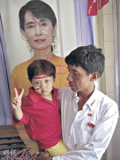 在Mayangon全民盟支部內,連小童也出來支持昂山素姬,與親人在素姬的海報前舉起勝利手勢拍照。(謝德健攝) 全民盟的競選車隊令道路變得像一條「紅絲帶」,如同勝利巡遊。(謝德健攝) 在Mayangon全民盟支部內,連小童也出來支持昂山素姬,與親人在素姬的海報前舉起勝利手勢拍照。(謝德健攝) 全民盟的競選車隊令道路變得像一條「紅絲帶」,如同勝利巡遊。(謝德健攝)