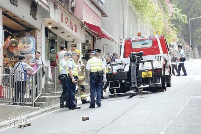 意外後警員在拖車(圖)附近調查,地上確留下兩枚相信是用來固定故障吊臂車車輪的木塊。(雲錦鋒攝) 意外後警員在拖車(圖)附近調查,地上確留下兩枚相信是用來固定故障吊臂車車輪的木塊。(雲錦鋒攝)