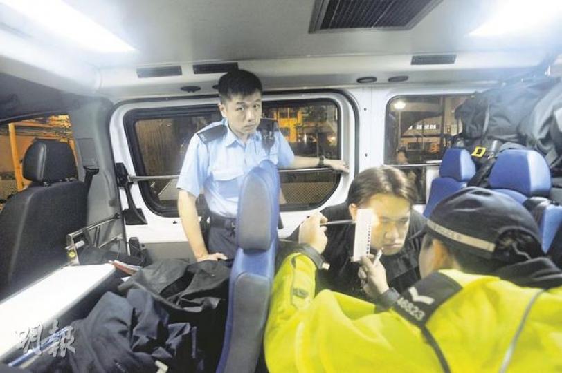 涉嫌藥駕司機被捕後,於警車上由警員量度瞳孔大小,警員拿圖表放在司機臉旁,與其瞳孔比對。(樊銳昌攝) 涉嫌藥駕司機被捕後,於警車上由警員量度瞳孔大小,警員拿圖表放在司機臉旁,與其瞳孔比對。(樊銳昌攝)