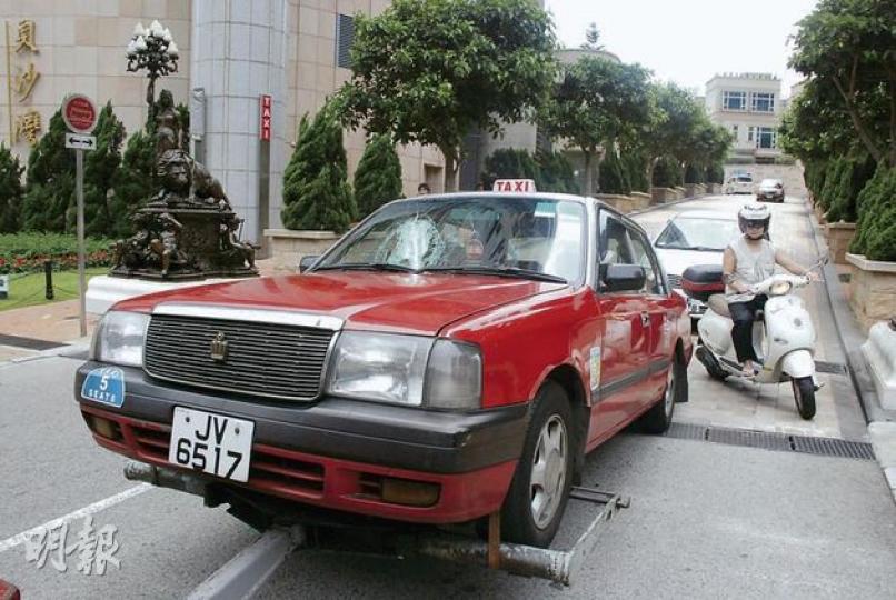 在貝沙灣二期南岸遭墜下鋁窗組件擊裂擋風玻璃之的士，由工程車拖走維修。（雲錦鋒攝）