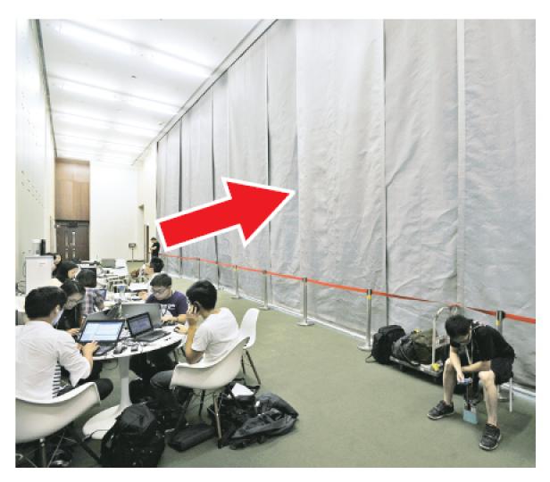 立法會1樓會議廳內一幅巨型防火幕（箭嘴示，貌似窗簾，火警時可隔煙隔火減慢火勢蔓延），昨清晨疑因故障，無故自行降下，之後防火幕便無法捲起收回，幸事件中無人受傷。（何家達攝）