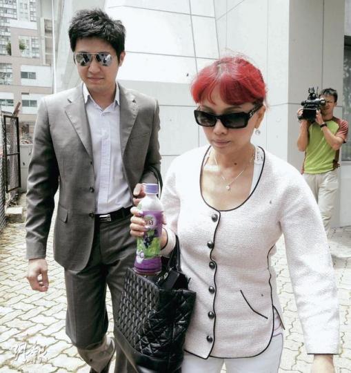 年約50歲的「美容女王」曾裕(前右)染了一頭紅髮,與丈夫李守義(左)一同離庭。李指現時一家出入均十分小心,女兒「去邊都一定叫人跟住」。(尹錦恩攝) 年約50歲的「美容女王」曾裕(前右)染了一頭紅髮,與丈夫李守義(左)一同離庭。李指現時一家出入均十分小心,女兒「去邊都一定叫人跟住」。(尹錦恩攝)