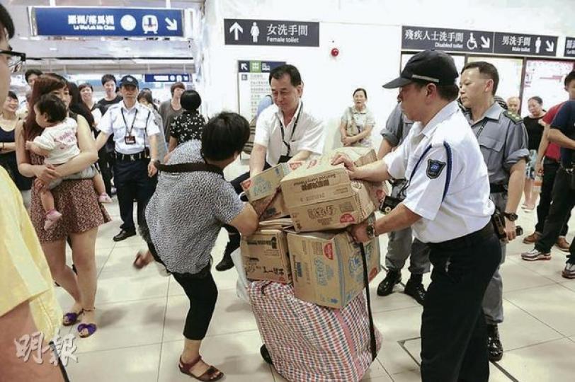 左手斷臂傷殘的謝婦，昨日在上水港鐵站因手推車體積過大，被港鐵職員拒絕入閘。其間與保安員多番拉扯，雙方爭執，謝婦曾因情緒激動「起腳」襲擊保安。（劉焌陶攝） 左手傷殘的謝婦及後被警員、保安和港鐵職員聯手制服，倒在地上。（劉焌陶攝）