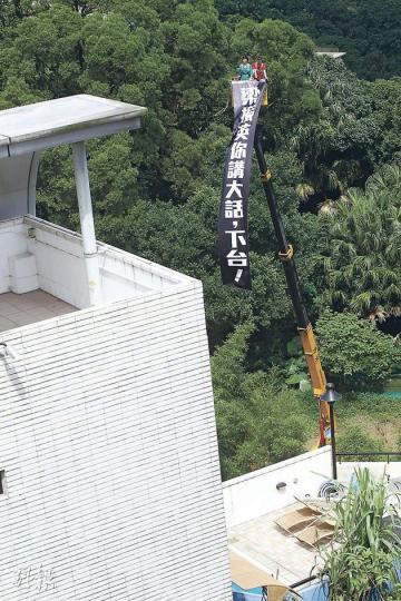 民主黨昨在梁振英山頂大宅外,以1800元租用吊臂車,將寫上「梁振英你講大話,下台!」的25呎長布條掛起,以示抗議。(李紹昌攝) 民主黨昨在梁振英山頂大宅外,以1800元租用吊臂車,將寫上「梁振英你講大話,下台!」的25呎長布條掛起,以示抗議。(李紹昌攝)