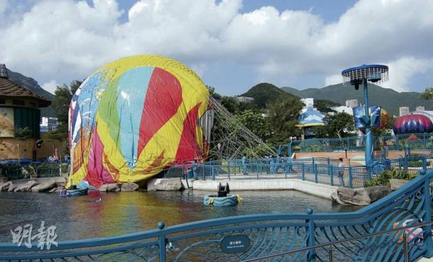海洋公園載人氦氣球因漏氣，昨在20米半空墜下，並被風吹至偏離安全降落區，載客籃內外共5名遊客受傷，圖為意外後正漏氣的氦氣球擱在湖邊。（曾立本攝） 氦氣球撞向旁邊的樹及花槽，擱在行人路，圖中可見載客籃之大，昨在地面被撞倒的遊客未有喪命實屬幸運。（伍浦鋒攝）