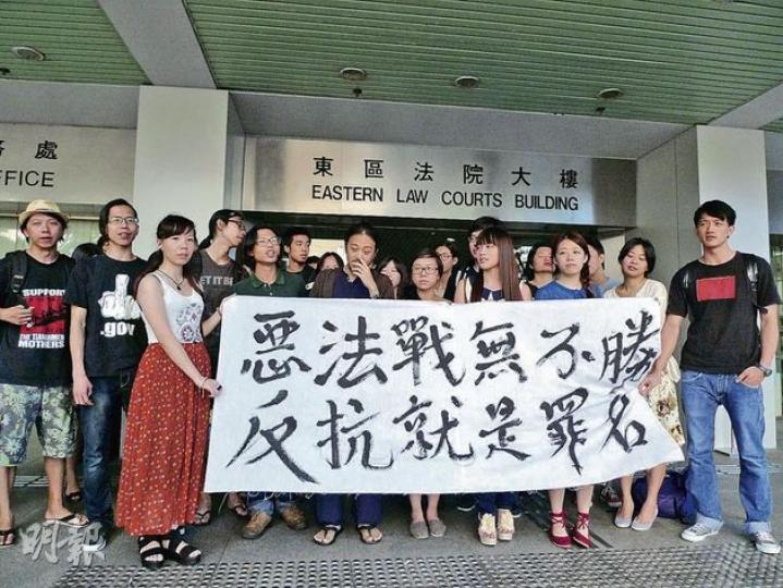 泰歷（綠衣者）獲大批同道中人歡呼歌唱，眾人在庭外拉橫額示威。（何偉畧攝） 被告泰歷笑言趕及重獲自由，極希望在七一上街遊行，他即問旁人「有無火」，準備抽煙。（何偉畧攝）