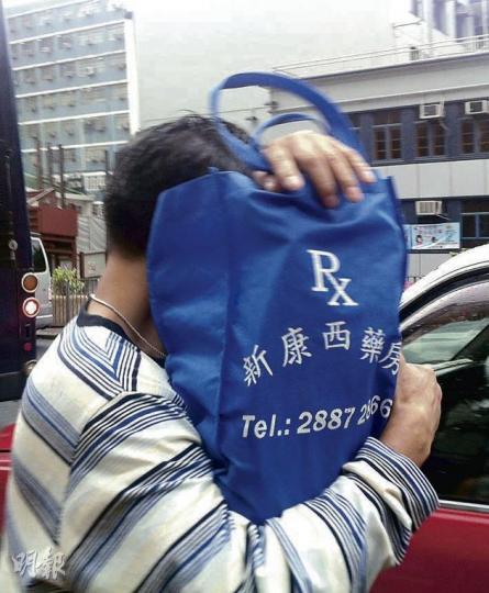 去年區議會油尖旺京士柏選區中，虛報假住址的被告李建源昨被判緩刑。他離開法庭時，全程以環保袋掩面。（余卓善攝）