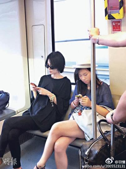 王菲與囡囡童童乘坐機場接駁列車,兩母女同樣低頭玩電話。(微博圖片) 王菲與囡囡童童乘坐機場接駁列車,兩母女同樣低頭玩電話。(微博圖片)