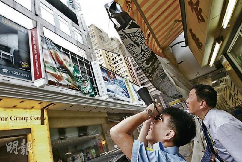颱風後市面不少外牆海報吹至搖搖欲墜,圖中灣仔英皇集團中心大廈的外牆海報,有保安員以望遠鏡檢視外牆情况。(李紹昌攝) 颱風後市面不少外牆海報吹至搖搖欲墜,圖中灣仔英皇集團中心大廈的外牆海報,有保安員以望遠鏡檢視外牆情况。(李紹昌攝)