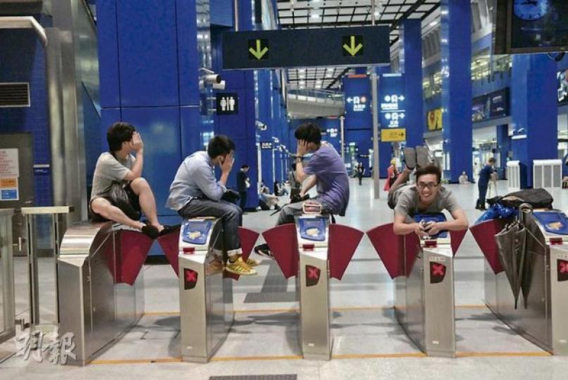 閘機當櫈坐 前日連續工作14小時的侍應陳先生(右一),深夜與3名同事欲乘東鐵返家,豈料因列車故障滯留大圍站一晚,他強烈不滿港鐵安排,特別是賠償與否有雙重標準的問題。(鍾炳然攝) 閘機當櫈坐 前日連續工作14小時的侍應陳先生(右一),深夜與3名同事欲乘東鐵返家,豈料因列車故障滯留大圍站一晚,他強烈不滿港鐵安排,特別是賠償與否有雙重標準的問題。(鍾炳然攝)