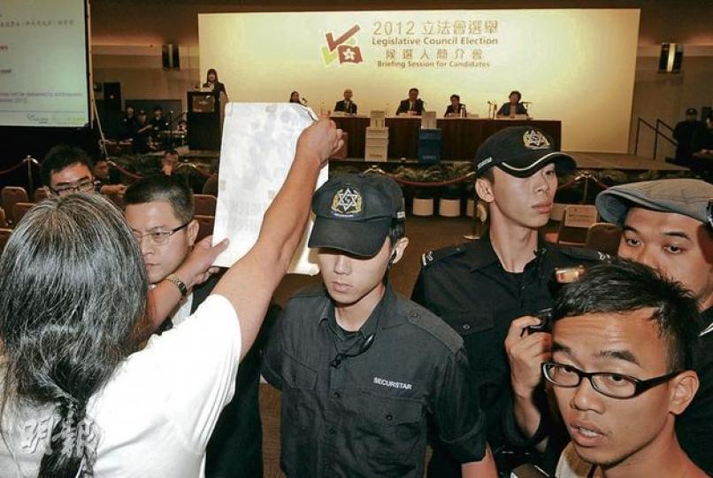選舉事務處昨晚舉行立法會候選人簡介會,社民連曾健成及梁國雄(左一)欲將「戰書」帶入會場,被保安拒絕進入,擾攘後兩人入內並舉起紙張,向台上的選管會主席馮驊抗議。(劉焌陶攝) 選舉事務處昨晚舉行立法會候選人簡介會,社民連曾健成及梁國雄(左一)欲將「戰書」帶入會場,被保安拒絕進入,擾攘後兩人入內並舉起紙張,向台上的選管會主席馮驊抗議。(劉焌陶攝)