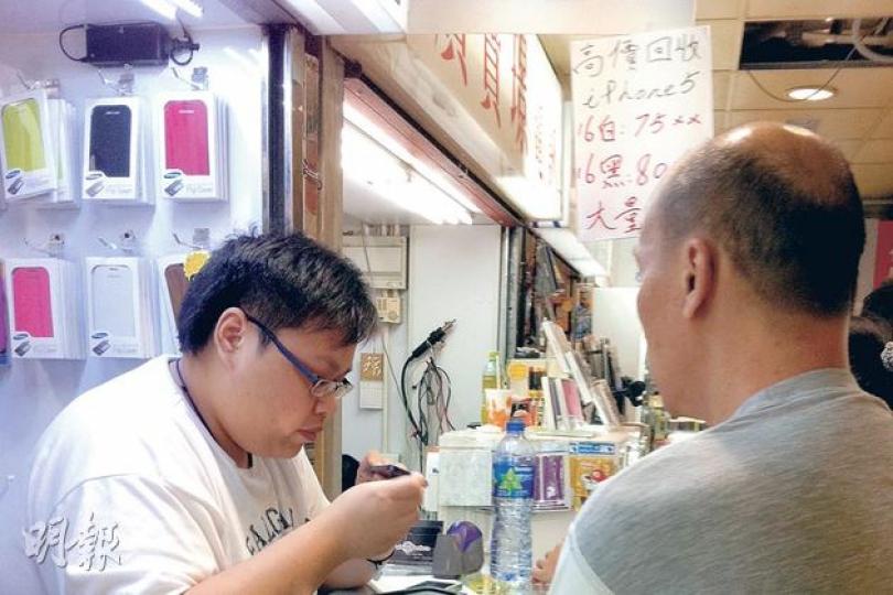 iPhone 5身價大跌，16GB版本昨日回收價已跌至7400元最低水平。圖為市民趕在跌價前將iPhone 5放給手機店。（明報記者攝）