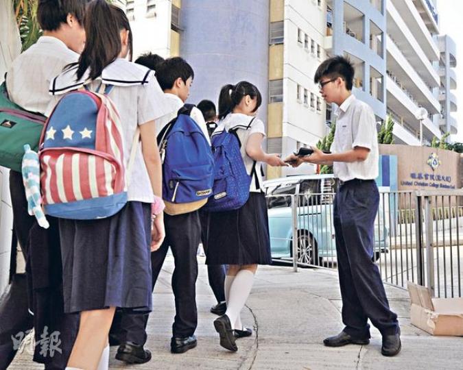 學民思潮召集人黃之鋒(右)昨日在上課前,於校門外向同學派發反洗腦小冊子,希望他們可更清楚國教科的問題。(葉家豪攝)(明報製圖) 學民思潮召集人黃之鋒(右)昨日在上課前,於校門外向同學派發反洗腦小冊子,希望他們可更清楚國教科的問題。(葉家豪攝)(明報製圖)