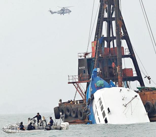 港燈客船「南丫四號」事發後一直由躉船懸吊,一半船身傾斜沒入海中,水警駕駛橡皮艇在躉船附近巡邏,直升機亦一直在上空盤旋。客船至昨下午被撈起。(李紹昌攝) 港燈客船「南丫四號」事發後一直由躉船懸吊,一半船身傾斜沒入海中,水警駕駛橡皮艇在躉船附近巡邏,直升機亦一直在上空盤旋。客船至昨下午被撈起。(李紹昌攝)