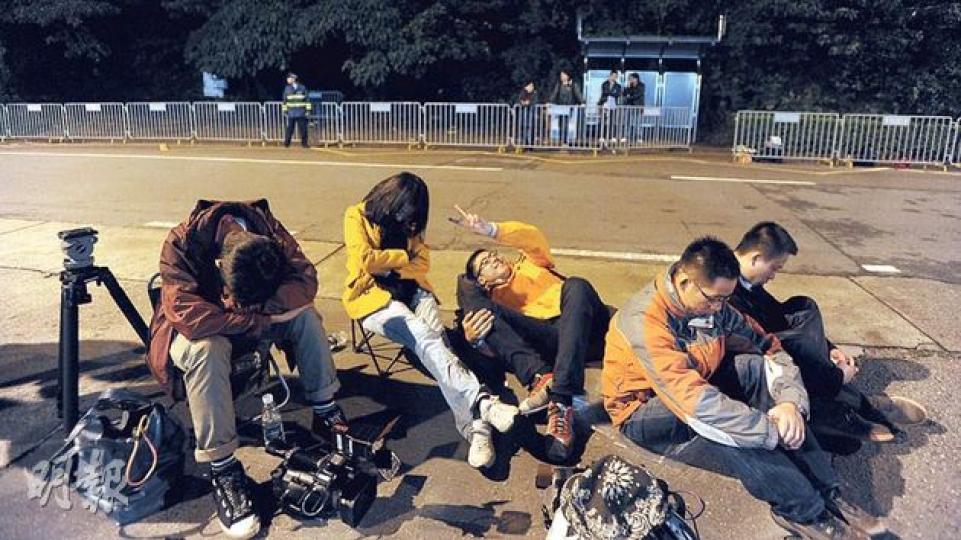 約50名記者前晚在澳門路環監獄外「又濕又冷」的環境下通宵等候尹國駒出獄，不少記者最後倦得坐在地上，不管地面濕滑。（余俊亮攝）