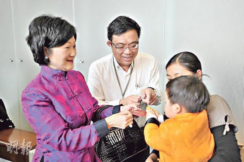 葉劉淑儀（左）向涂謹申（中）仔仔信之（橙衣者）派利市。（葉家豪攝）