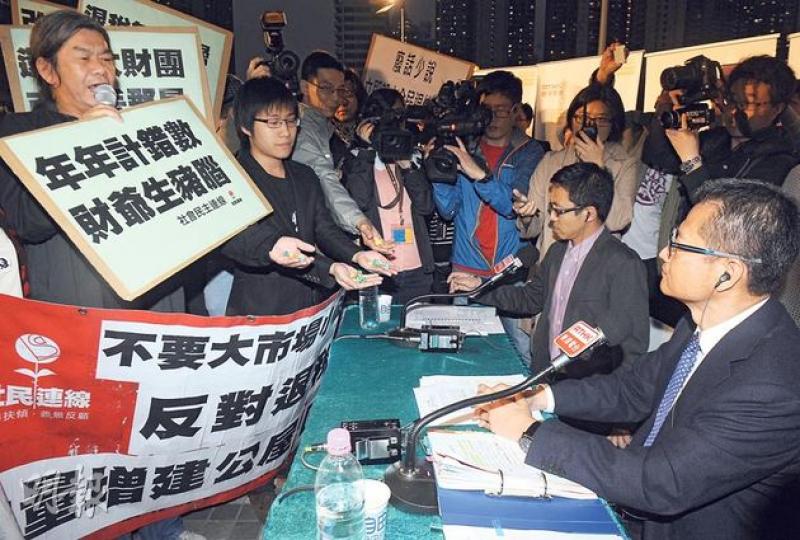 社民連梁國雄（左一）昨晚趁發展局長陳茂波（右一）到黃大仙廣場出席港台節目《自由風自由PHONE》時示威，送紙星星給他，諷刺財政司長曾俊華在預算案提及的「遙望繁星」。（劉焌陶攝）