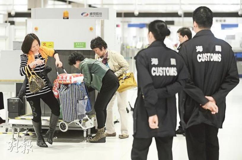海關於9個出入境口岸加設X光機及抽調人手檢查旅客行李。圖為落馬洲支線口岸關員以Ｘ光機檢查持大件行李過境的旅客，以了解行李中有否超額奶粉。（余俊亮攝）