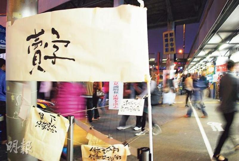 「賣字」幾乎每周擺檔,小小攤檔不吵不阻人,卻屢遭驅趕,近月落戶尖沙嘴天星碼頭,與法輪功橫額及街板為鄰,「筆者」笑言是體驗「和諧」,且該處人流多元,互動較多。(袁柏恩攝) 「賣字」幾乎每周擺檔,小小攤檔不吵不阻人,卻屢遭驅趕,近月落戶尖沙嘴天星碼頭,與法輪功橫額及街板為鄰,「筆者」笑言是體驗「和諧」,且該處人流多元,互動較多。(袁柏恩攝)