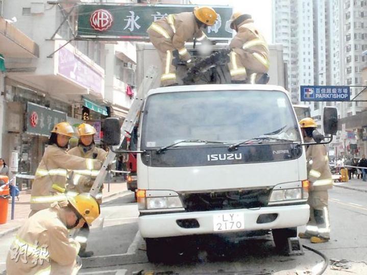 消防員正在檢視爆炸的冷凍貨車，事件中碎片飛彈10米外擊傷兩名女途人。（鍾炳然攝）