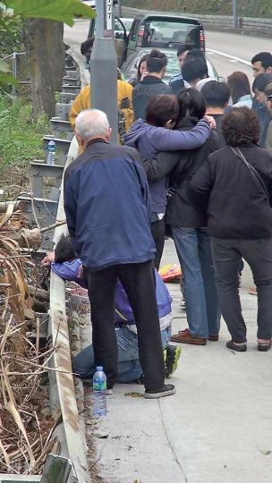 死者家人昨重返現場拜祭時傷心不已,其父(紫衣者)更跪在地上,頭撼路邊防撞欄傷心痛哭,死者母親亦情緒激動,需人攙扶。(林智傑攝) 死者家人昨重返現場拜祭時傷心不已,其父(紫衣者)更跪在地上,頭撼路邊防撞欄傷心痛哭,死者母親亦情緒激動,需人攙扶。(林智傑攝)