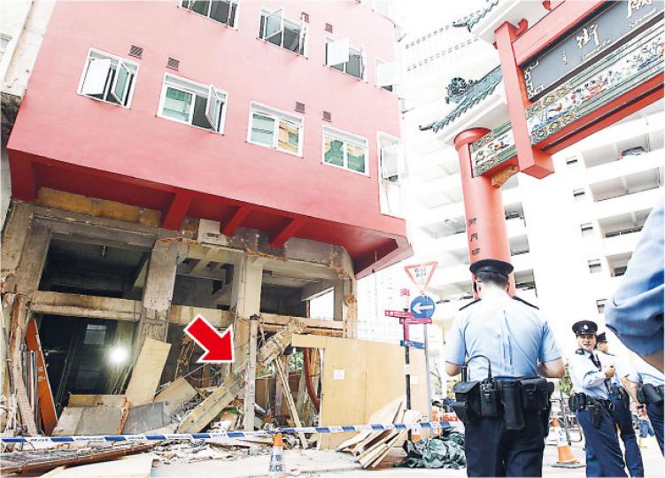油麻地地舖發生塌石屎門楣傷人意外，唐樓地舖鐵閘頂約10米長石屎門楣（箭嘴示）塌下，一名工人被擊中埋瓦礫中重傷。現場所見，消防員事後用粗麻繩固定傾斜的門楣，等候有關人員到場調查。（李紹昌攝）意外後，政府人員到場調查及拍攝蒐證，初步證實唐樓結構未有危險。（李紹昌攝）