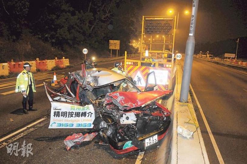 的士昨凌晨撞上停在快線的公路維修車，右邊車頭先撞入車底，再「打白鴿轉」在路面打轉數圈始停下，車頭嚴重損毁，的士司機傷重斃命。（蔡方山攝）肇事工程車車斗上雖備有指示牌及雪糕筒等（右），在意外前並未有放置路面以提醒尾隨司機。工程車司機（圖）未有受傷，留在現場協助警方調查。（蔡方山攝）